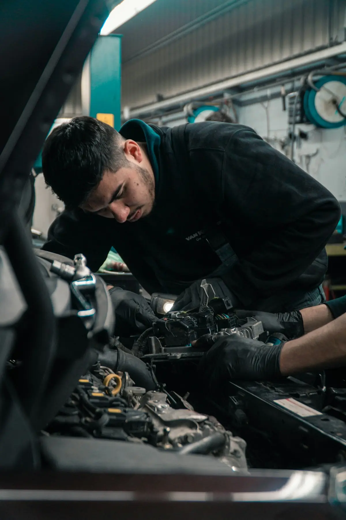 Mechanic working under the hood with a work light